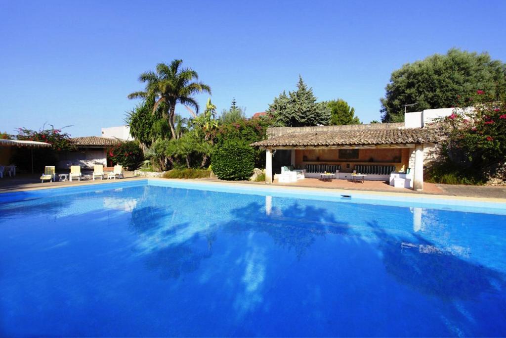 uma grande piscina azul em frente a uma casa em Villa del Commendatore Sirugo em Avola