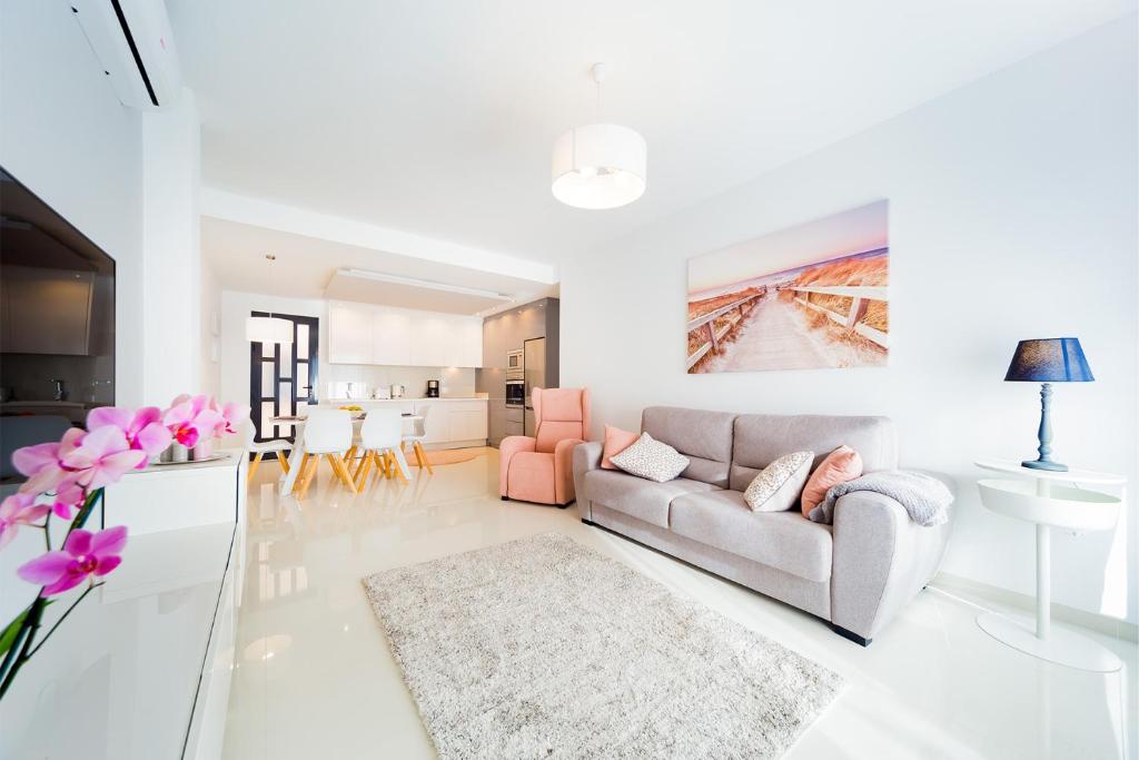 Biały salon z szarą kanapą i różowymi krzesłami w obiekcie Luxurious 2 Bedroom Apartment near the beach w mieście La Horadada