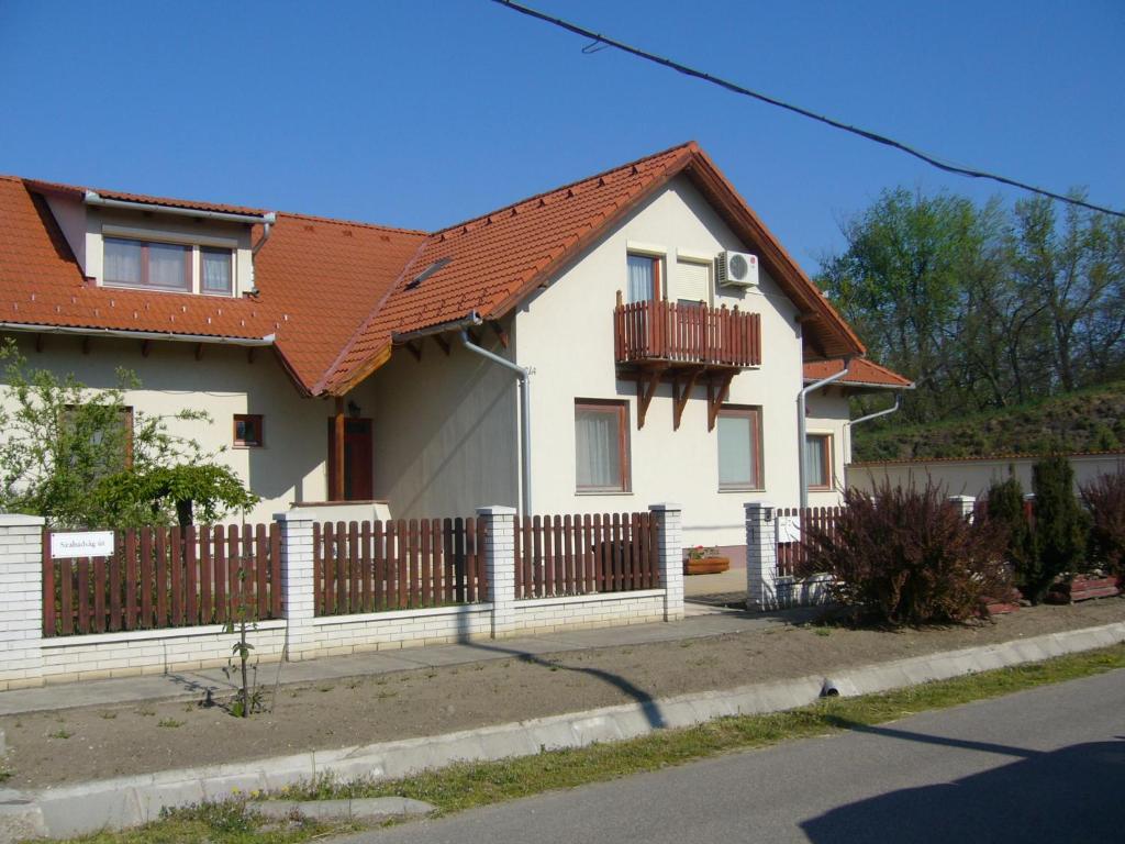 a white house with a wooden fence at Csipkeház Apartman in Cserkeszőlő