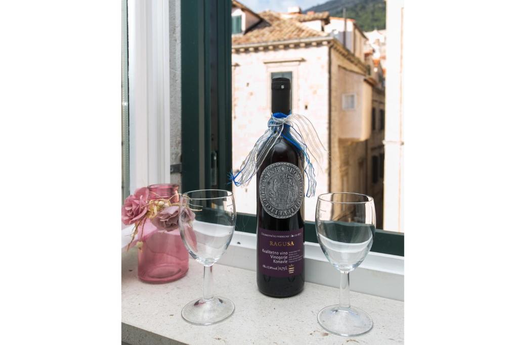 a bottle of wine and two wine glasses on a window at Lumin Guest House in Dubrovnik