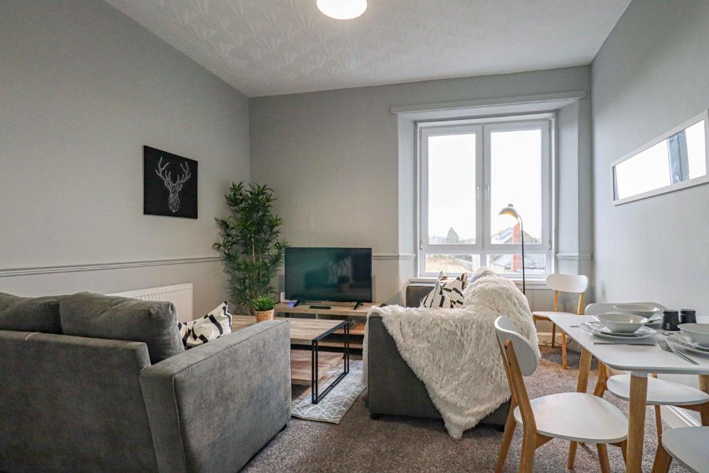 a living room with two couches and a tv at Townend Apartment in Dumbarton
