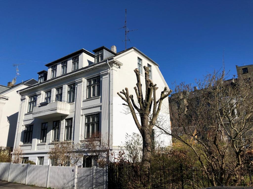 a white house with a tree in front of it at Rooms in quiet white villa apartment Hortensiavej 8 on Frederiksberg C in Copenhagen