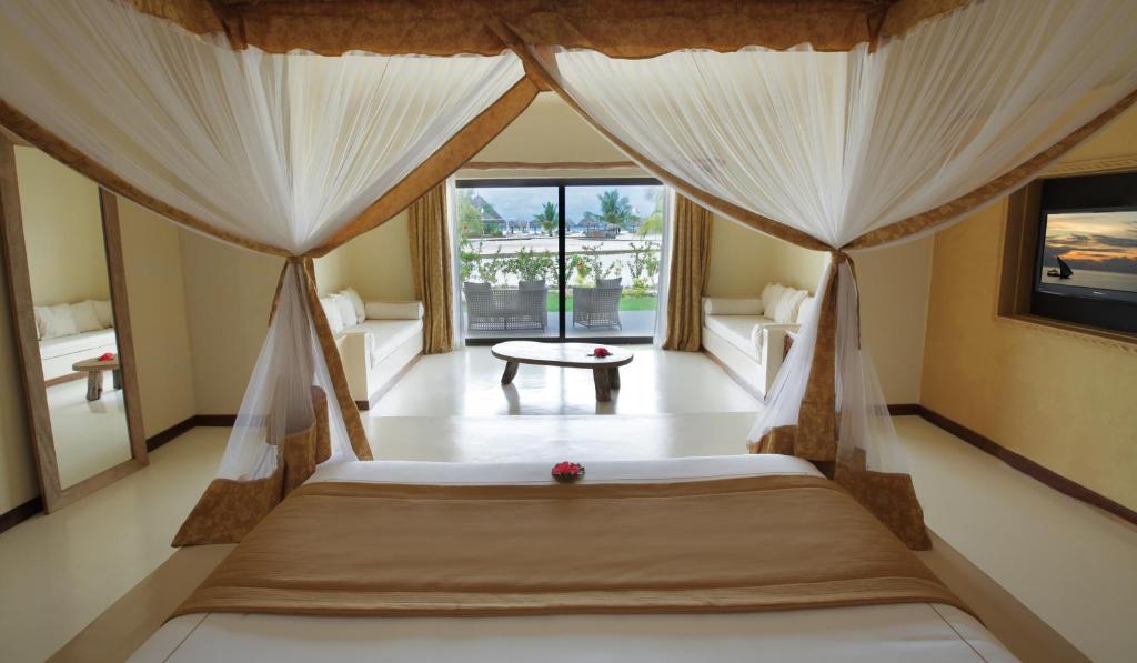 a bedroom with a bed with curtains and a table at Gold Zanzibar Beach House & Spa in Kendwa