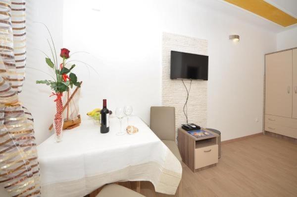 Dieses weiße Zimmer verfügt über einen Tisch mit Weingläsern und einen TV. in der Unterkunft Guest House Mia in Split