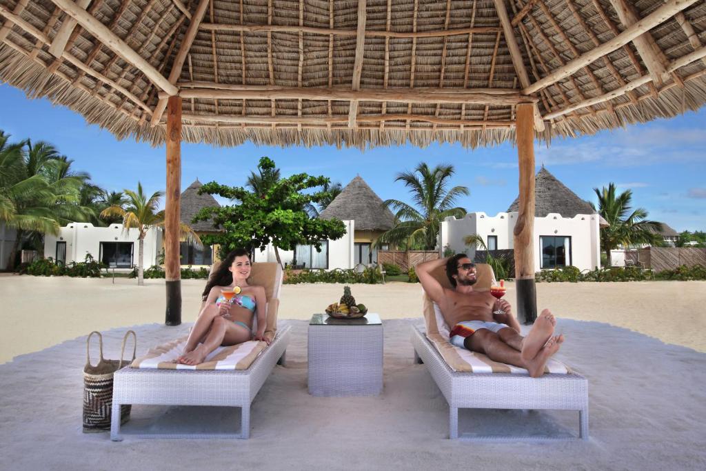 a man and a woman sitting on chairs on the beach at Gold Zanzibar Beach House & Spa in Kendwa