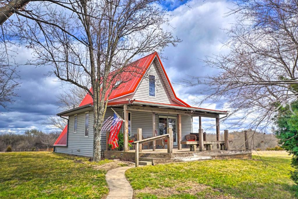 a small house with a red roof on a field at Vivid Cedar Ridge Cabin about 23 Miles to Wichita! in Augusta