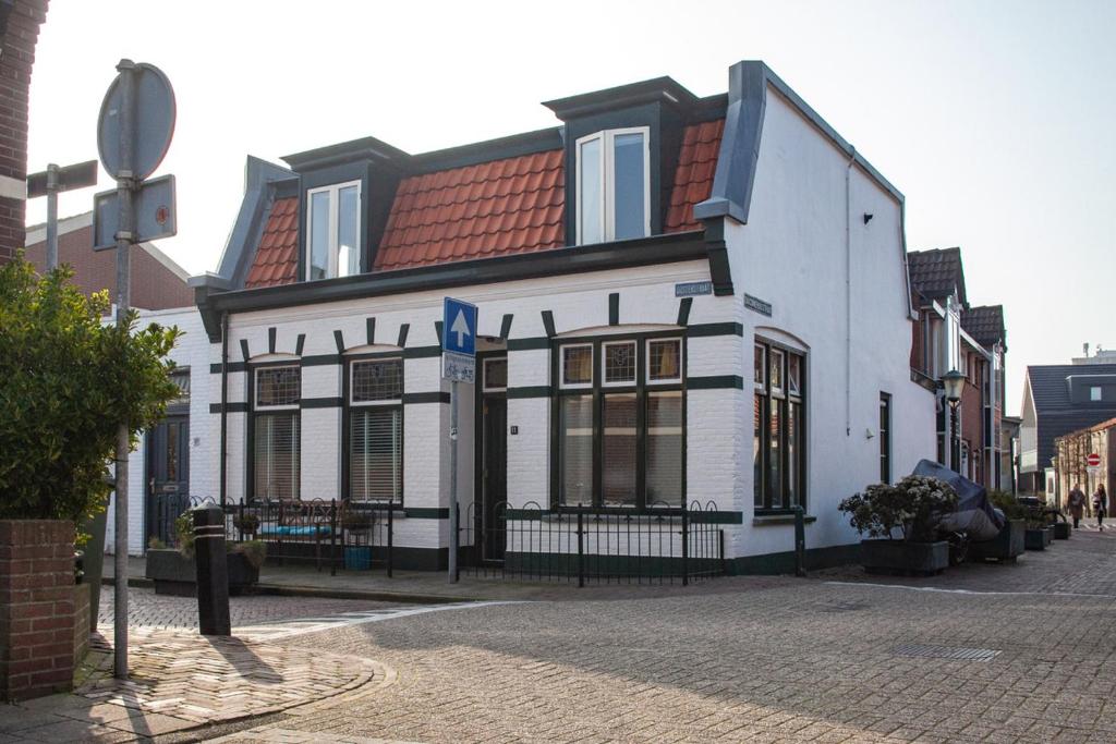 un bâtiment blanc avec un toit rouge dans une rue dans l'établissement Oosterhouse, à Zandvoort