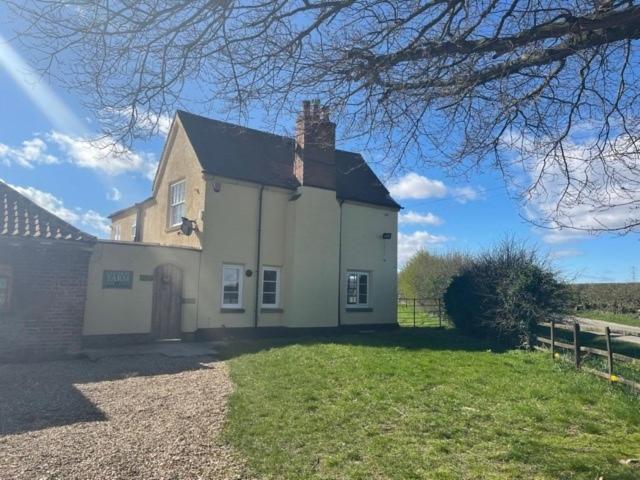 a large white house with a gate and a fence at Common Farmhouse in Newark-on-Trent