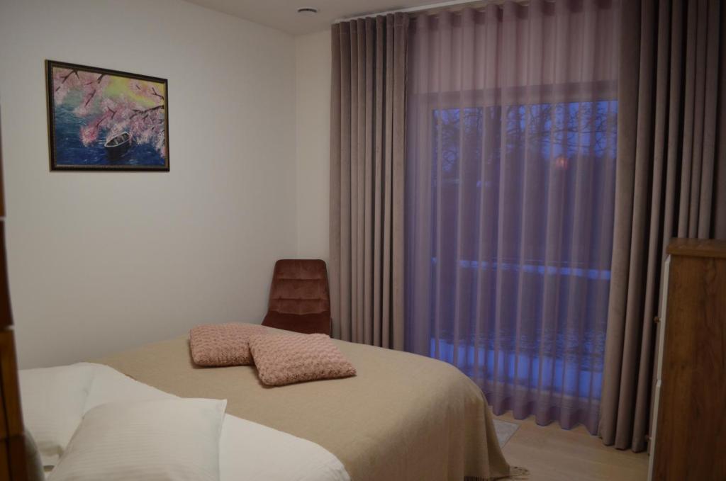 a bedroom with a bed and a window with purple curtains at Ravila Puhkemaja in Kuressaare