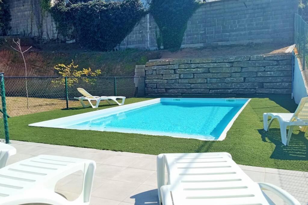 een zwembad met twee witte stoelen ernaast bij Villa Valentina in Girona