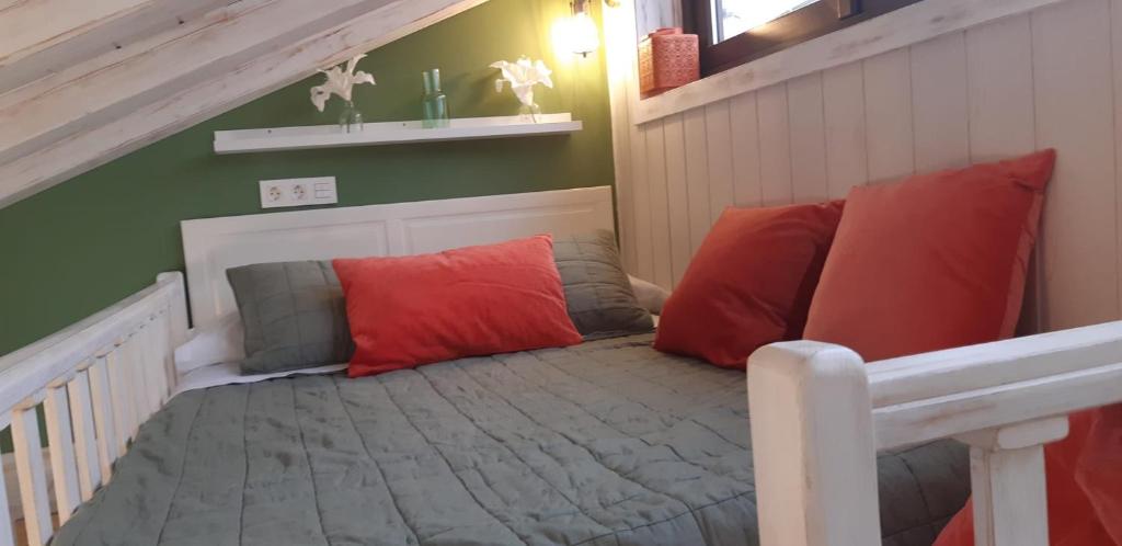 1 cama con almohadas rojas y grises en una habitación en Apartamentos A Poniente en Villanueva de la Concepción