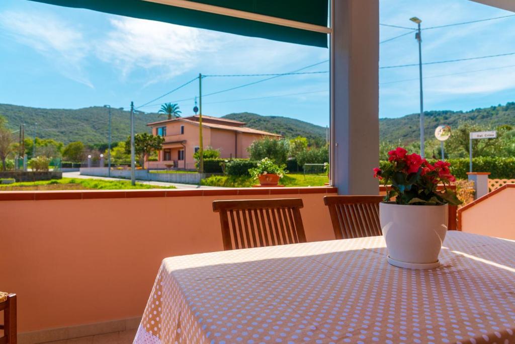 a table with a vase of flowers on a table with a window at Appartamento Passeggiata Al Mare in Campo nell'Elba