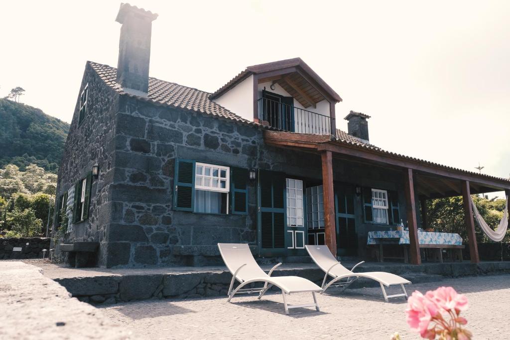 two chairs and a house with a building at Baía de Canas Villa in São Roque do Pico