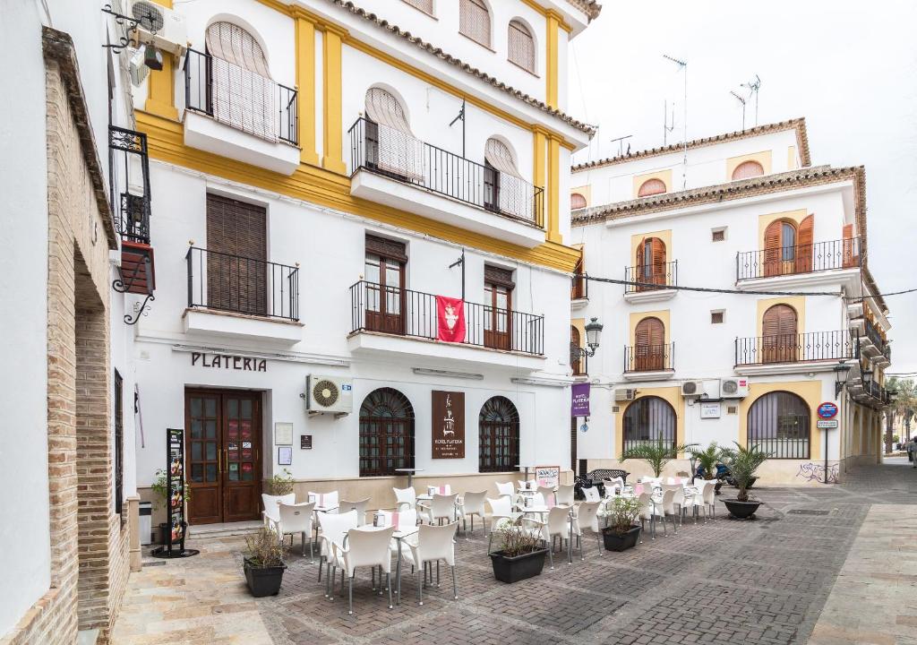 a building with tables and chairs in a courtyard at Hotel Platería in Écija
