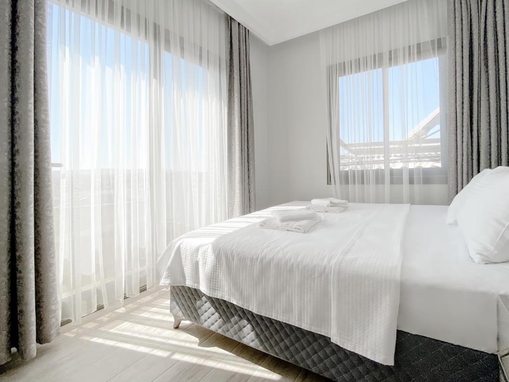 a white bedroom with a bed and a large window at Azize Palas Apart Otel in Izmir