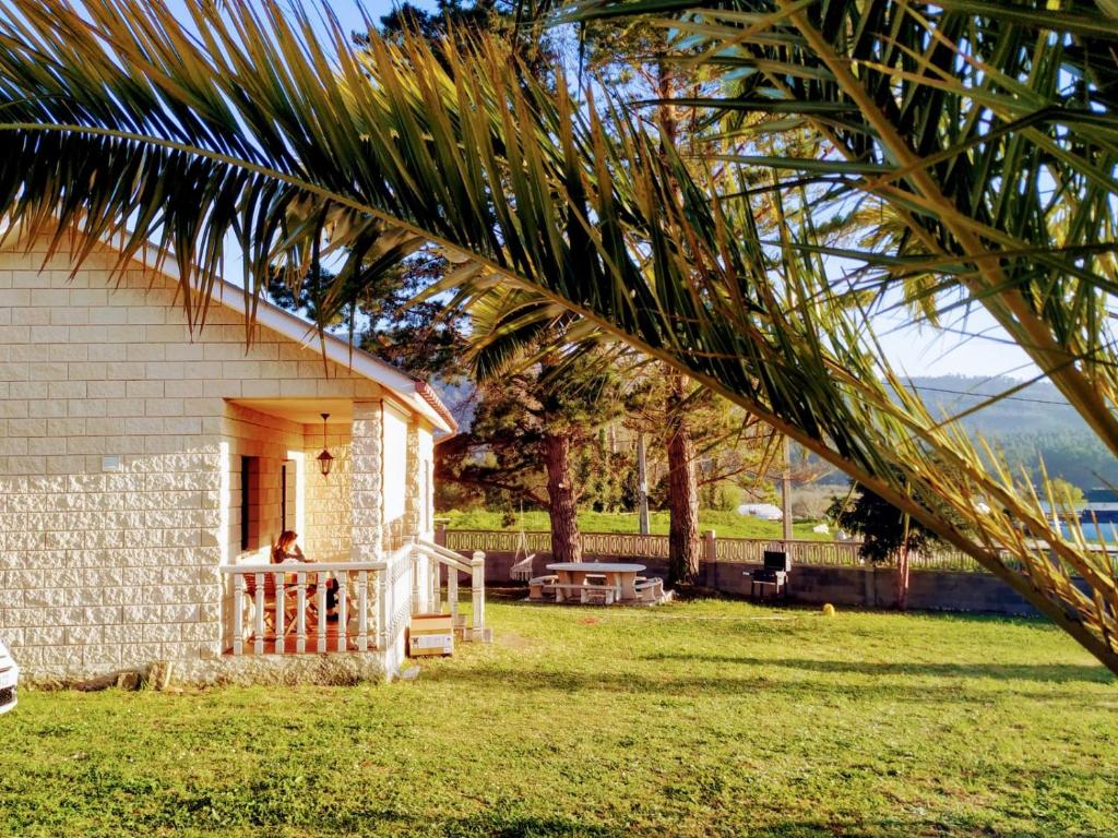 una persona sentada en el porche de una casa en Casa en la playa de Area con finca privada, en Viveiro