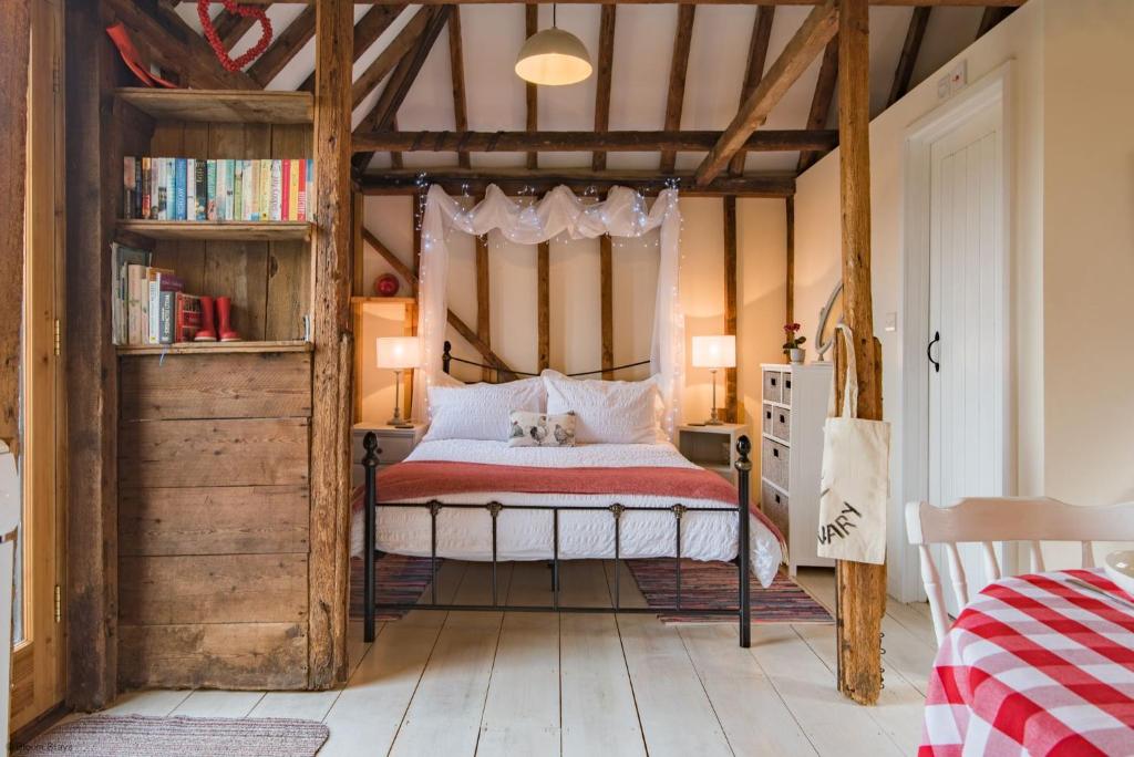 a bedroom with a canopy bed and a book shelf at The Granary by Bloom Stays in Canterbury