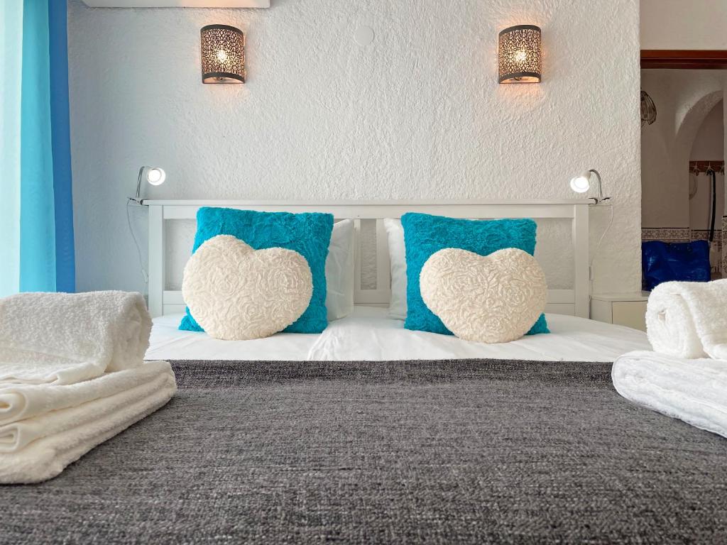 Una cama con almohadas azules y blancas con corazones. en Algarve Sol Beach House, en Quarteira