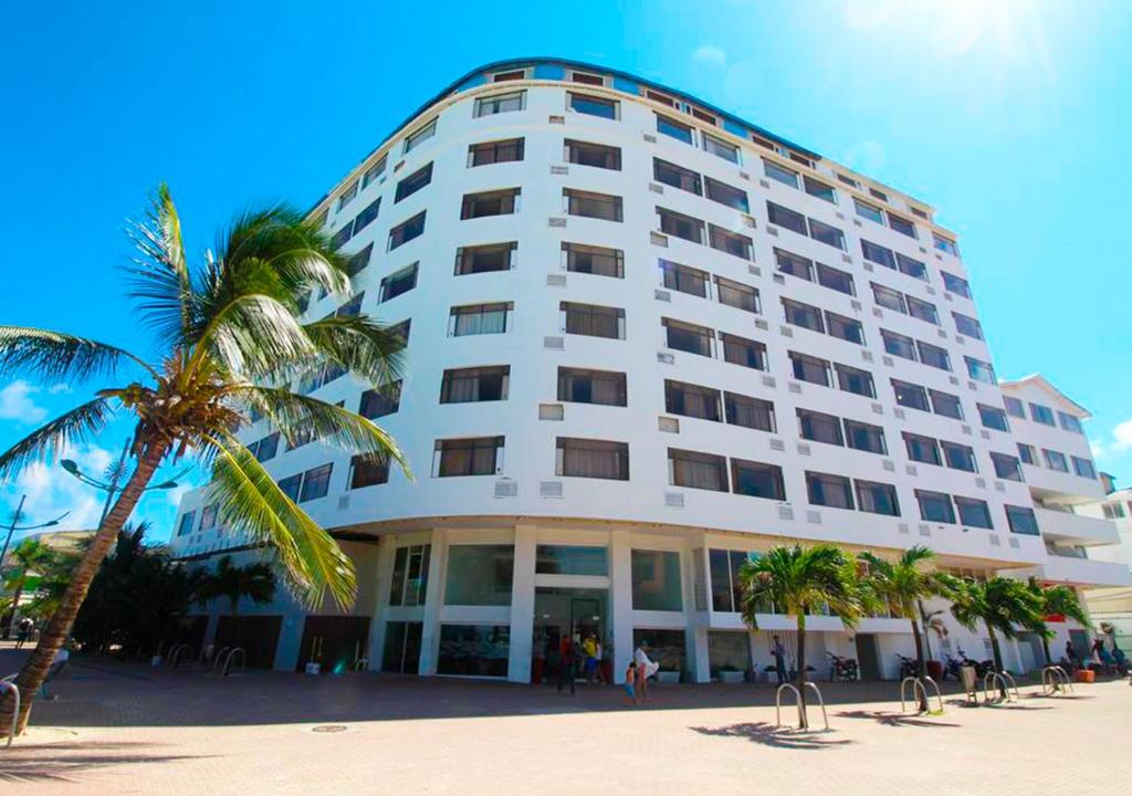 een groot wit gebouw op het strand met een palmboom bij On Vacation Blue Tone in San Andrés