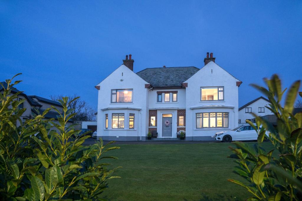 Uma casa branca com um carro à frente. em Larkhill House em Portrush