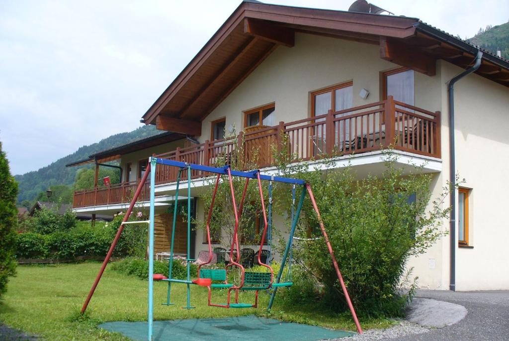 un parque infantil frente a una casa con balcón en Golf & Ski Appartements Lesak, en Zell am See