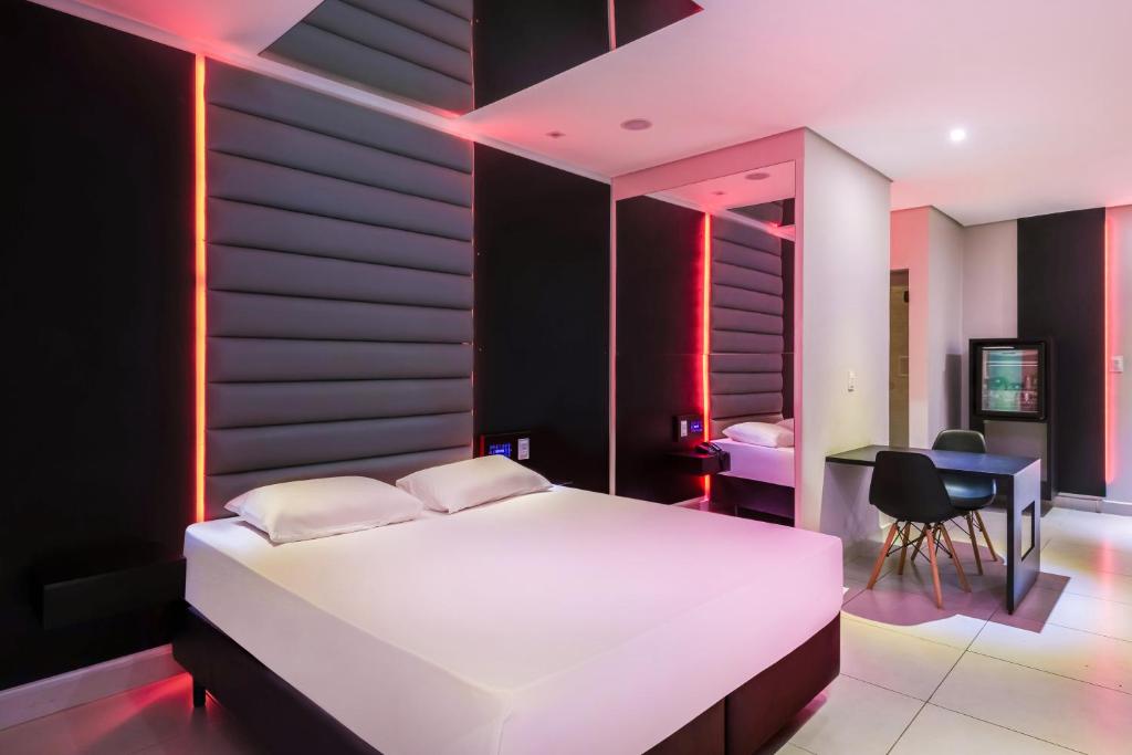 sypialnia z dużym białym łóżkiem i biurkiem w obiekcie Plaza Motel w mieście Sorocaba