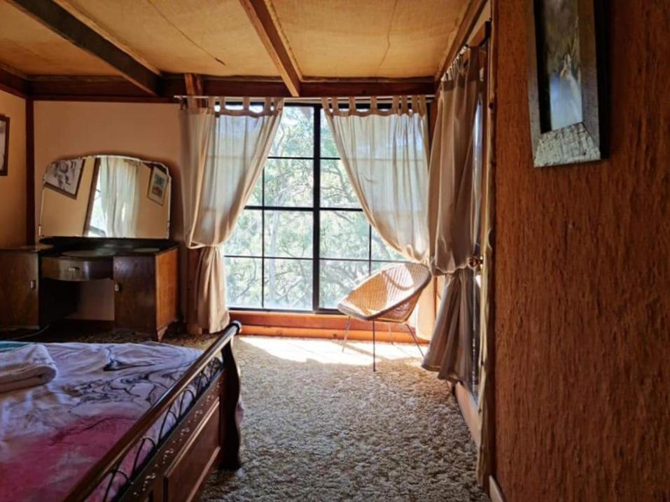 ein Schlafzimmer mit einem Bett und einem großen Fenster in der Unterkunft Shady Creek Eco Cabin, Mudgee, Peaceful Country Getaway in Grattai