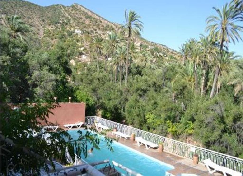 une piscine avec bancs et une montagne en arrière-plan dans l'établissement Maison d'hôtes tifrit-Paradise valley, à Imouzzer