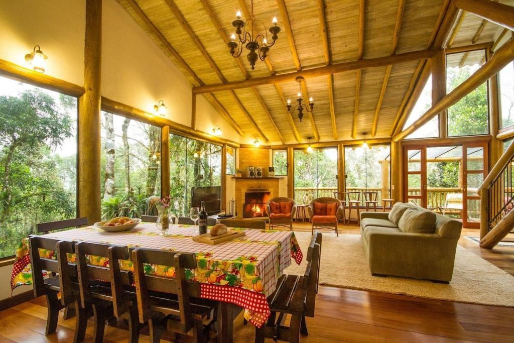 uma grande sala de estar com uma mesa e um sofá em Natureza e área gourmet em Campos do Jordão em Campos do Jordão