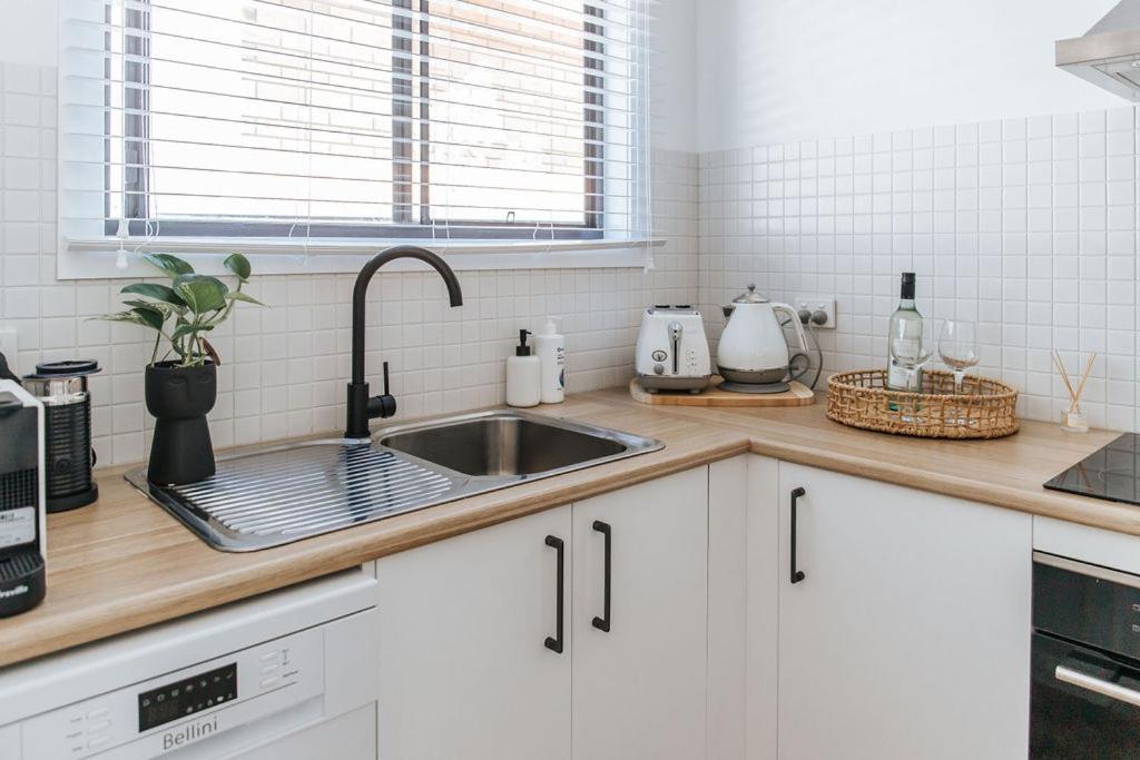 una cucina con armadi bianchi e lavandino di Studio on Lewis Tiny House a Mudgee