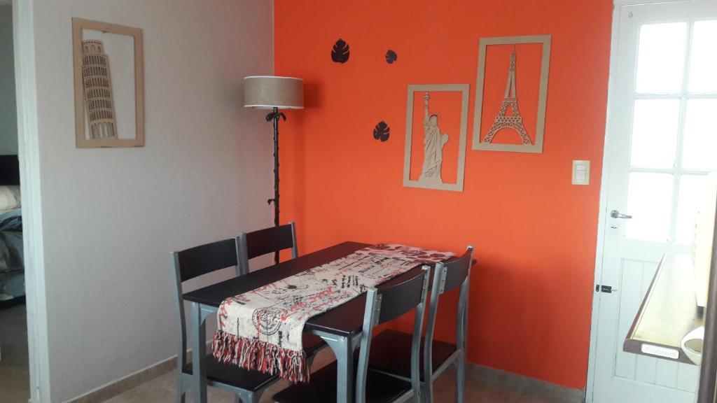 ein Esszimmer mit einer orangefarbenen Wand mit einem Tisch und Stühlen in der Unterkunft Departamento cerca Parque Termal II Belgrano 1486 in Dolores