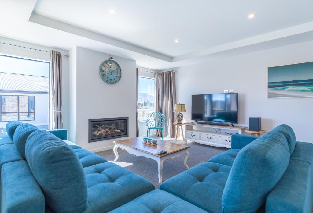 a living room with a blue couch and a tv at Neptune - Lake Tekapo in Lake Tekapo
