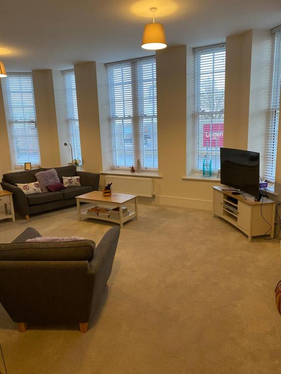 a living room with couches and a flat screen tv at Chichester Luxury One Bed Apartment in Chichester