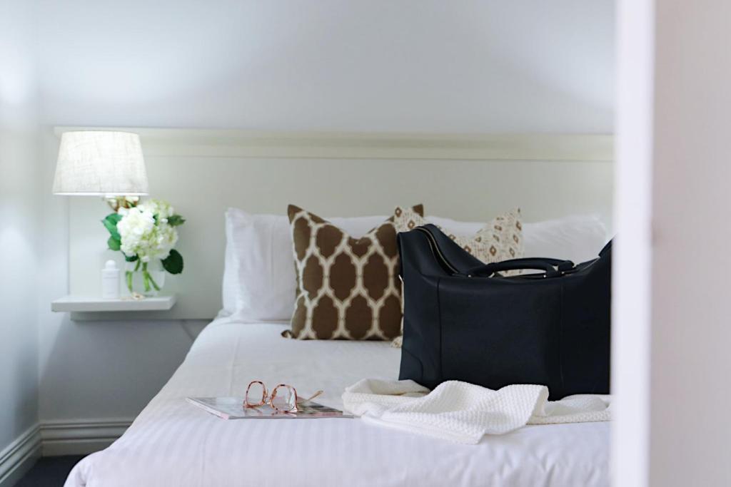 uma cama com um saco preto e sapatos em Hotel Collins em Melbourne