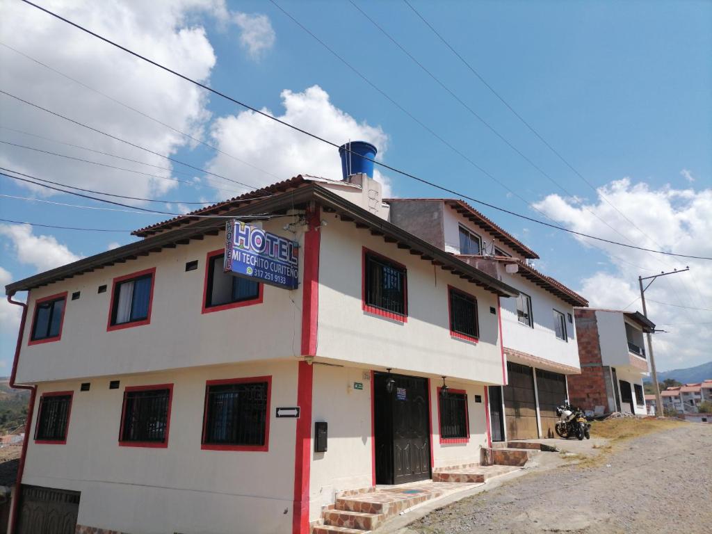 un edificio blanco con una señal azul en Mi Techito Curiteño, en Curití