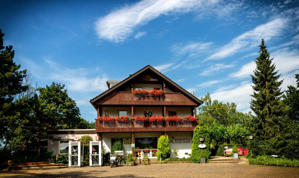 ein Gebäude mit einem Balkon mit roten Blumen darauf in der Unterkunft Berghotel Hohe Mark in Reken