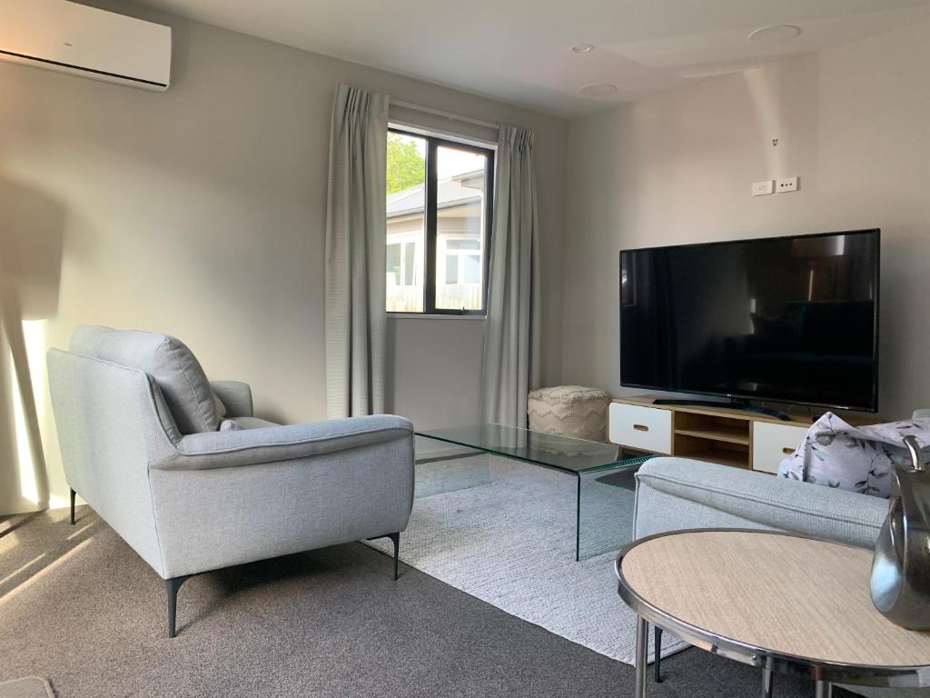 a living room with two chairs and a television at Stylish Oasis in central city in Christchurch