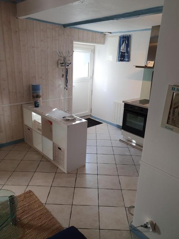 a kitchen with a tiled floor and a white cabinet at penty vero in Plobannalec-Lesconil