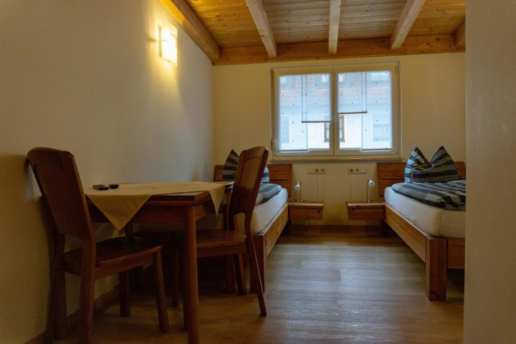 ein Esszimmer mit einem Tisch, Stühlen und einem Fenster in der Unterkunft Gästehaus Familie John in Veitsbronn