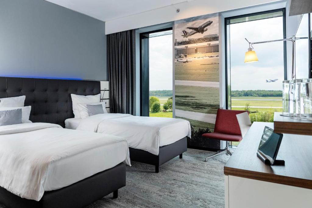 een hotelkamer met 2 bedden en een raam bij Airport Plaza Hotel Hamburg in Norderstedt