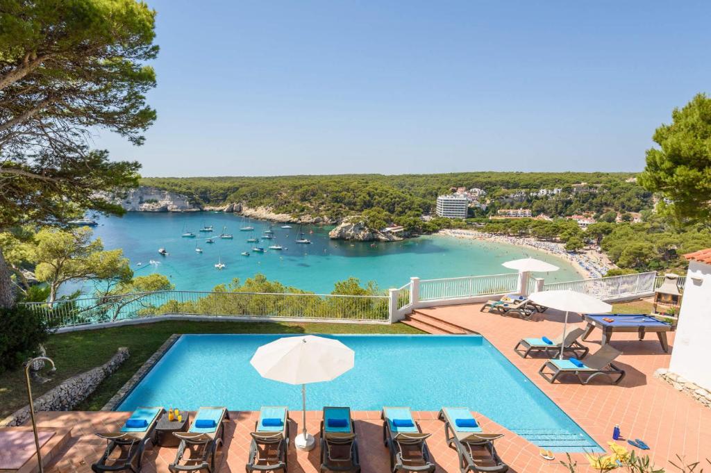 a swimming pool with chairs and a view of a lake at Villa Pinar by Villa Plus in Ferreries