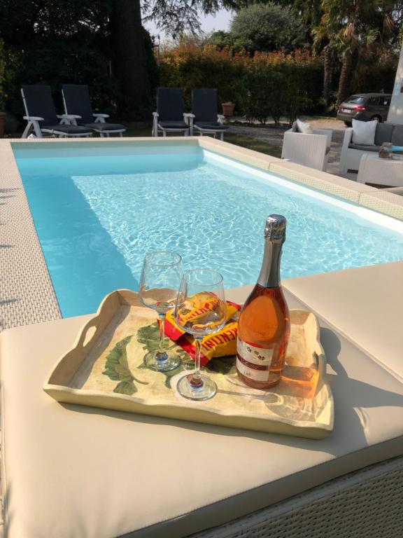 a tray with a bottle and glasses next to a swimming pool at Betty's House in Lazise