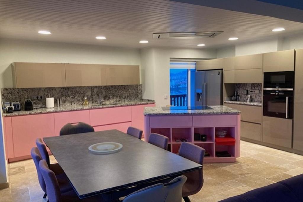 a kitchen with a dining table and a kitchen with pink cabinets at nivelle in Saint-Jean-de-Luz