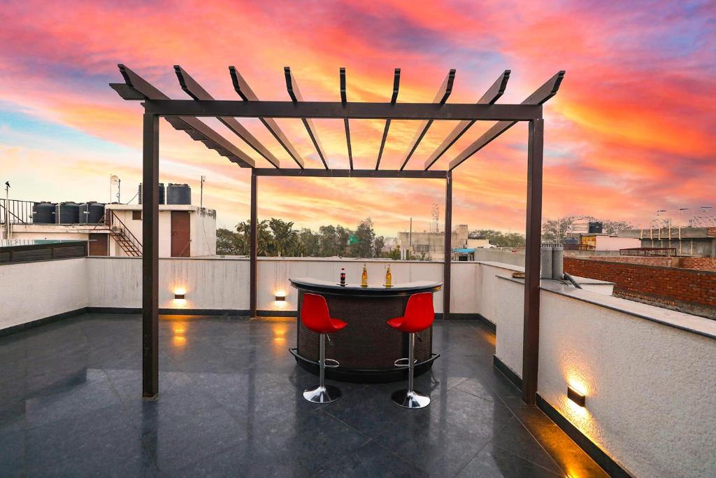 a bar on the roof of a building with a sunset at FabHotel La Paz Stay B&B in New Delhi