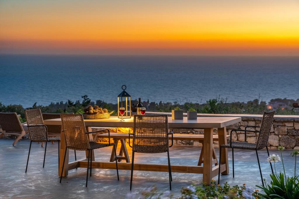 a dining table and chairs with a view of the ocean at Blue Horizon Cottages in Tzamarelláta
