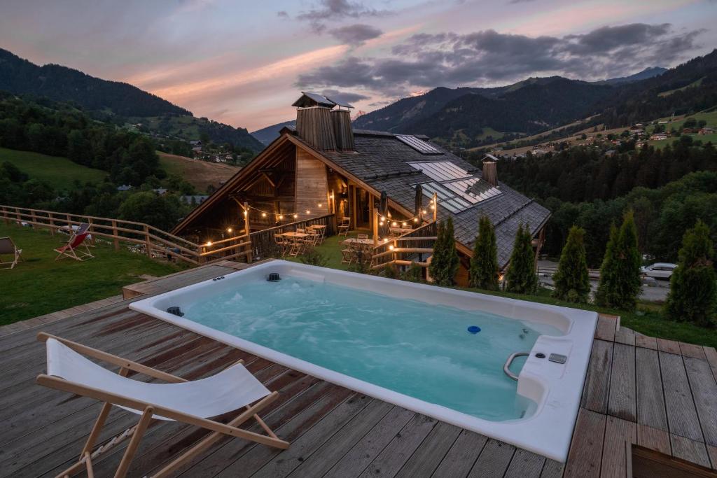 a hot tub on a deck next to a house at LE TOI DU MONDE in Flumet