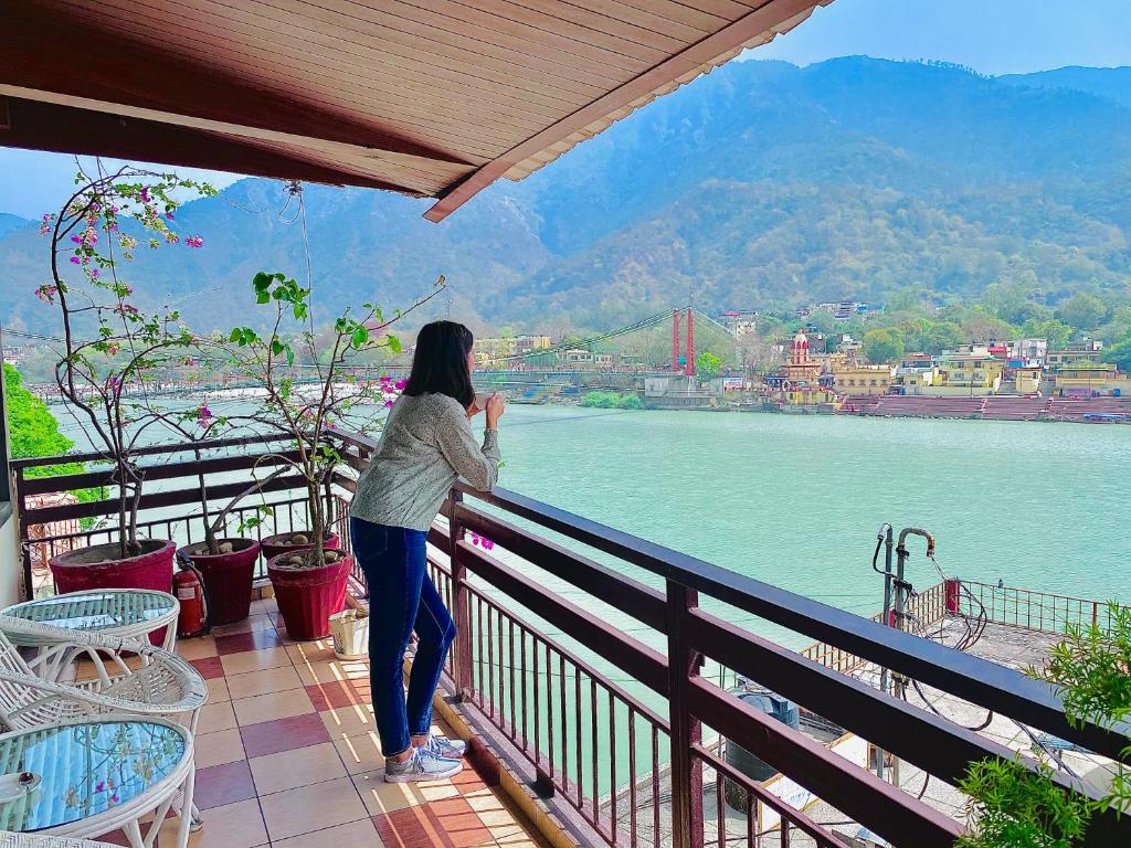 a woman standing on a balcony looking at the water at Sanskriti Vedic Retreat in Rishīkesh
