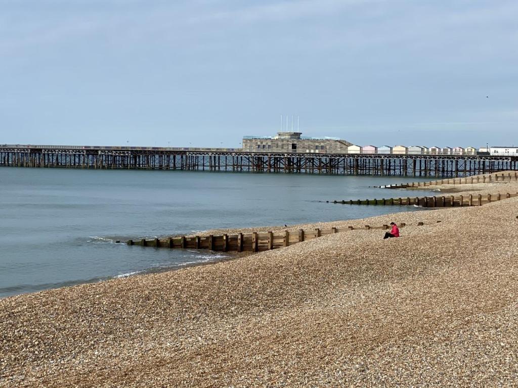 una persona sentada en la playa cerca de un muelle en Astral Lodge, en Hastings