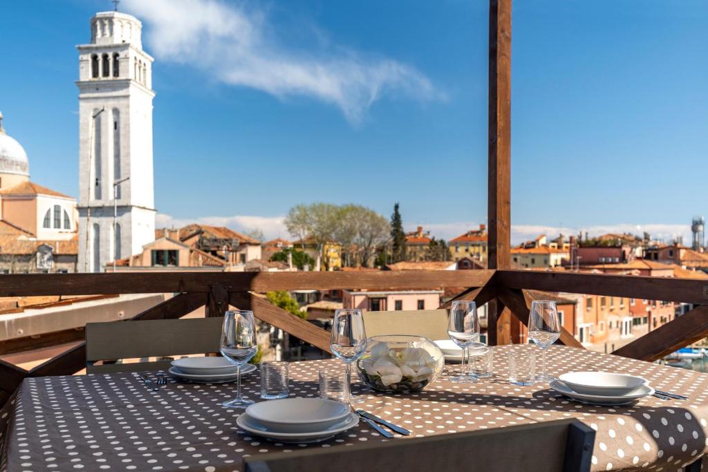 einen Tisch mit Tellern und Gläsern auf einem Balkon mit Turm in der Unterkunft Sea to Sky Apartments in Venedig