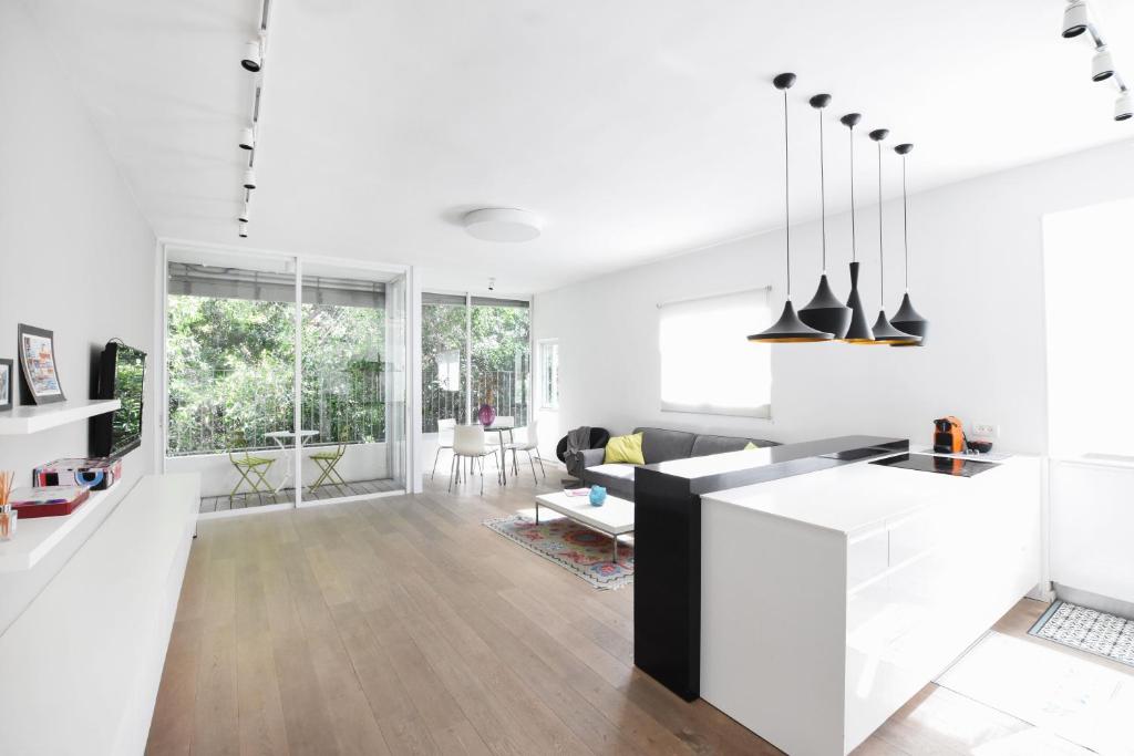 cocina y sala de estar con paredes blancas y suelo de madera en Light Ivory by HolyGuest, en Tel Aviv